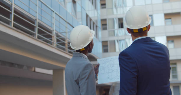 istock Back view of diverse industrial engineers planning on blueprint at work site. 1491486334