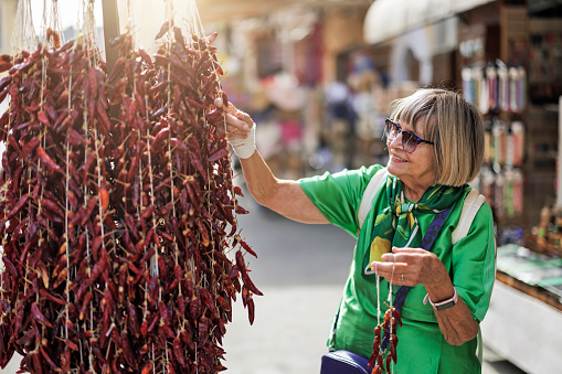 Senior woman buying dried Calabrian chili peppers on street market\nCanon R5