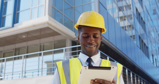 istock Business architect man wearing hardhat and west standing outdoors of building using digital tablet 1491487198