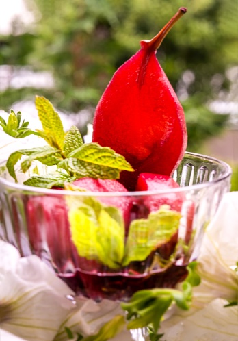 pear dessert in red wine and mint leaves in a glass vase