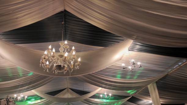 istock Yellow lamped chandelier next to white lamp on the ceiling light grey decorations in wedding party 1491494690