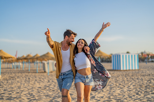 Young couple spending time together at the beach, celebrating success.