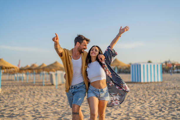 młoda para spędzająca razem czas na plaży, świętując sukces. - young adult beach people cheerful zdjęcia i obrazy z banku zdjęć