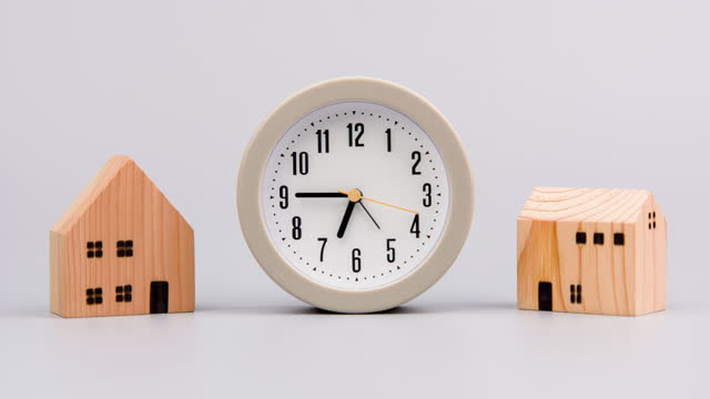Time and houses. A speeding clock is placed next to two houses. Home and time concepts, investing in real estate, building a house, building a house, wooden house, model house