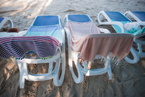 Deck chairs on the beach with towels on them