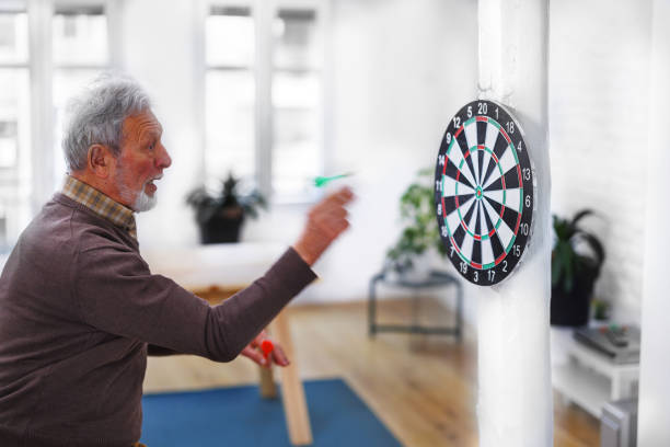 istock A senior man is playing darts at his home apartment. 1491497449