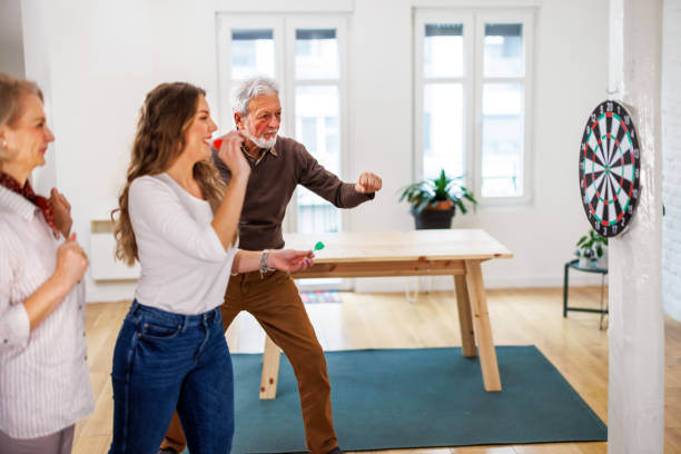 una pareja de ancianos está jugando a los dardos en un apartamento de casa. - dartboard photography competition sports and fitness fotografías e imágenes de stock