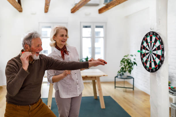 istock A senior couple is playing darts at a home apartment. 1491497658