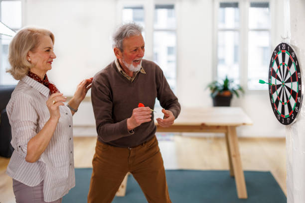 istock A senior couple is playing darts at a home apartment. 1491497724