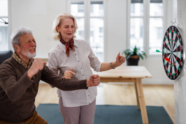 istock A senior couple is playing darts at a home apartment. 1491497907