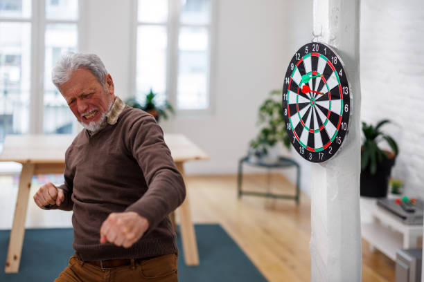 istock A cheerful senior is having a party and enjoying a dart game. 1491498014
