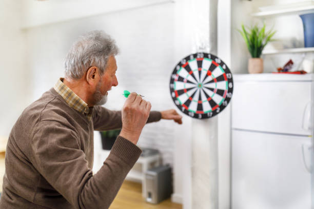 istock A senior man is playing darts at his home apartment. 1491499050