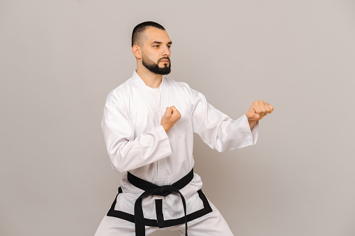 Dynamic image of young girls in dobok and helmet, taekwondo fighters training isolated over white background. Concept of martial arts, combat sport, competition. Banner. Empty space to insert text