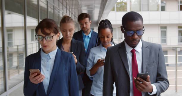 Multiethnic business team with gadgets going along urban building.