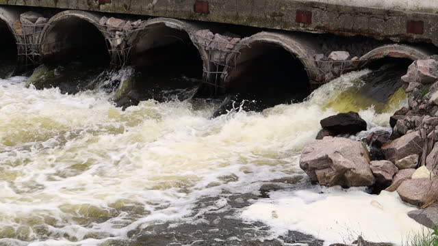 Environmental pollution, environmental disaster. Discharge of polluted sewage into the river from factory concrete pipes. Hazardous waste water. Environmental protection. Water pollution.