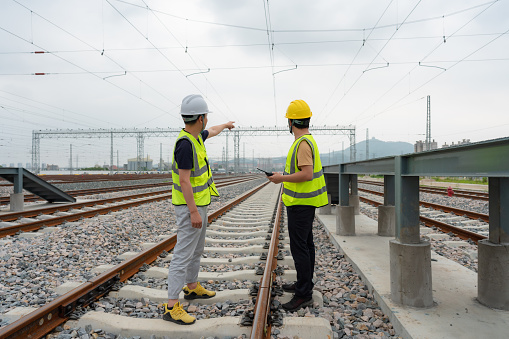 Two workers are inspecting and repairing the railway tracks at the train depot