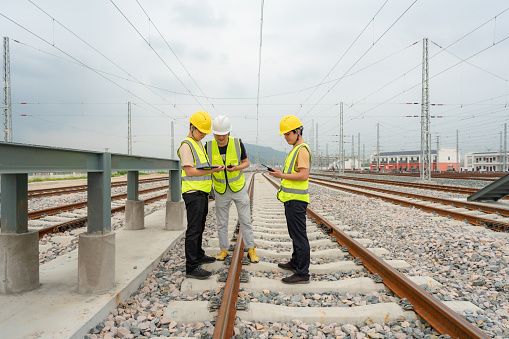 At the train depot, three engineers are inspecting the newly built railway tracks