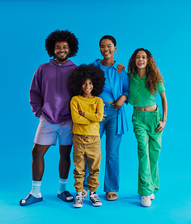 Small group of young black people standing, looking into the camera smiling and laughing whilst wearing multi colored clothing with copy space, stock photo