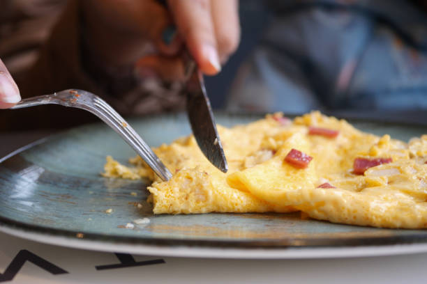 プレーンエッグオムレツを食べる女性 - omelet breakfast eggs onion ストックフォトと画像