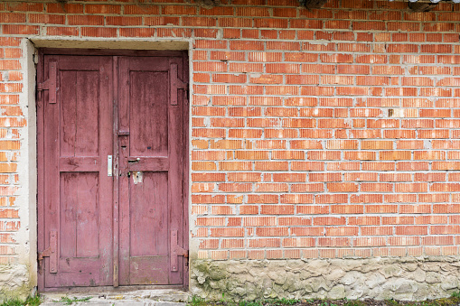 A red brick wall with a brown wooden door in it