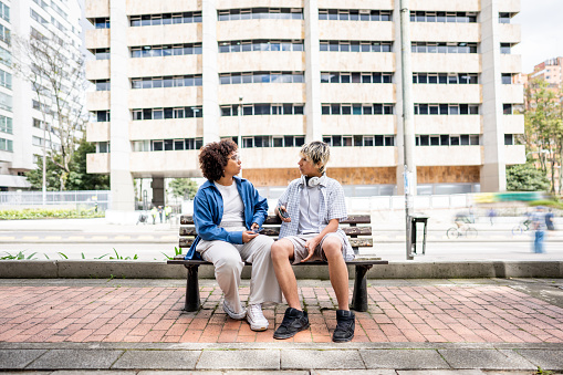 Young friends talking sitting on a bench outdoors