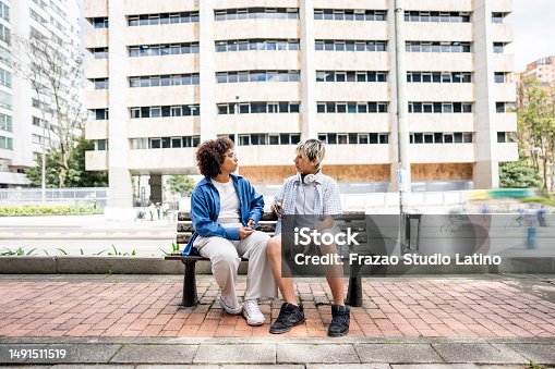 istock Young friends talking sitting on a bench outdoors 1491511519