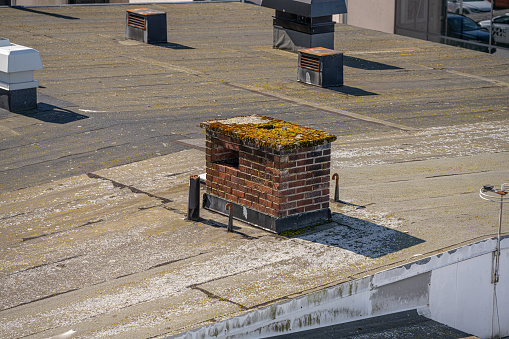 Old brick chimney on the roof of a warehouse.