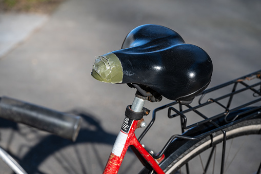Tape mended bicycle seat on a red bike.