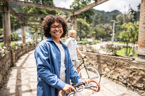Portrait of a young woman strolling with bicycle at public park