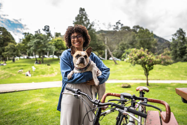 公共の公園でフレンチブルドッグを腕に抱く若い女性 - pets embracing one person portrait ストックフォトと画像