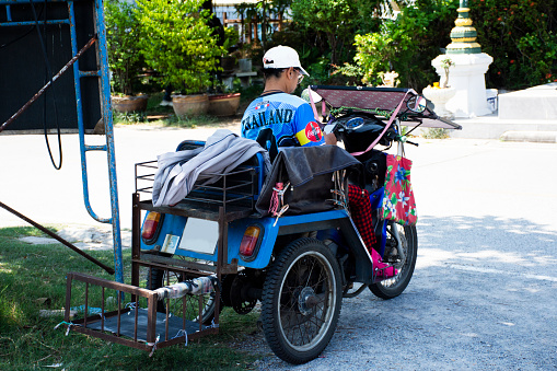 Handicapped tricycle motorcycle or three wheels motor wheelchair for disabled thai women people ride or bike stop in parking outdoor for sale lottery at Wat Ku on May 7, 2023 in Nonthaburi, Thailand