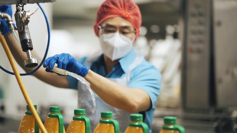 Asian Chinese male orange juice factory worker sealing bottle cap of orange juice in production line