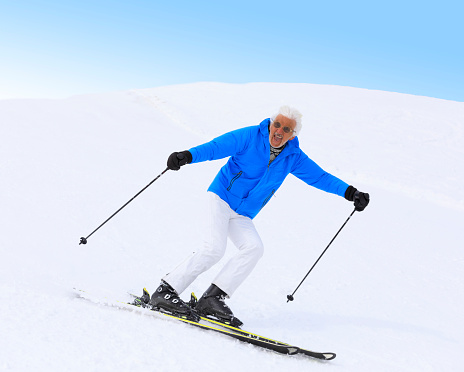 Vital senior, gray-haired men snow skier skiing, enjoying on  ski resorts. Skiing carving at high speed