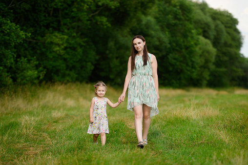 Portraits of joyful mother and daughter spend time together, enjoy happy family time, walk in the park. The concept of a happy family, family day,mother's day, countryside vacation, unity with nature.
