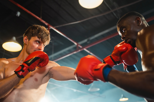 Two professional boxers are fighting on boxing ring, sportsmen boxing in the fight on square stage, or sport exercising with trainer at boxing and self defense lesson studio background, Thai Box match