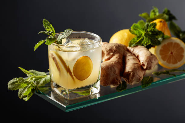 cocktail di birra ginger ale con limone e menta in un bicchiere ghiacciato su sfondo nero. - ginger tea root hot drink foto e immagini stock