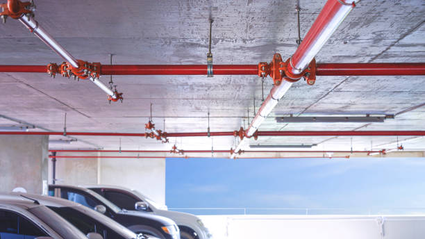 Red fire protective water pipeline system on concrete ceiling inside of parking garage building