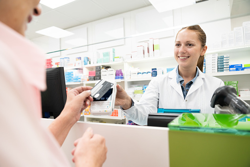 Senior woman paying contactless at pharmacy checkout