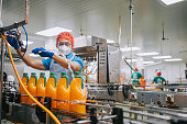 Asian Chinese male juice factory worker cleaning juice bottle with water hose in production line stock photo