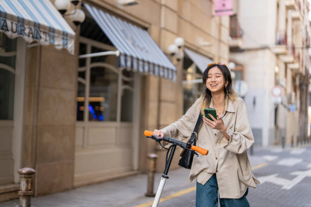 istock Female tourist Chinese ethnicity, using mobile app for navigation, while exploring city with electric push scooter 1491532346