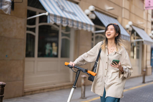 istock Female tourist Chinese ethnicity, using mobile app for navigation, while exploring city with electric push scooter 1491532417