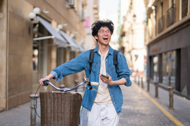 istock Happy Asian male tourist exploring city while pushing bicycle 1491532640
