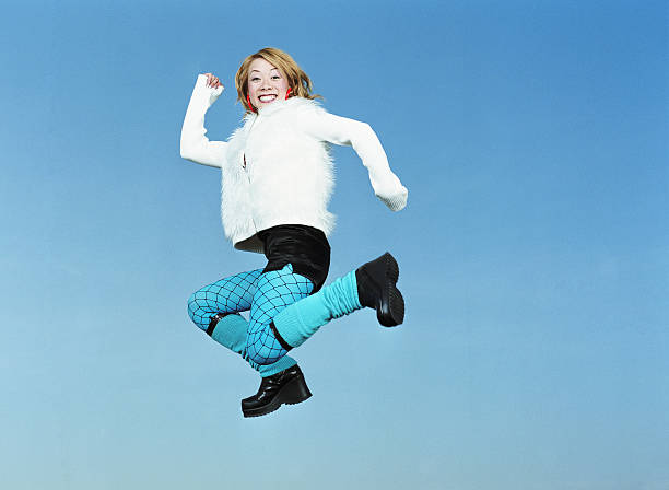 Young woman jumping in air, portrait, low angle