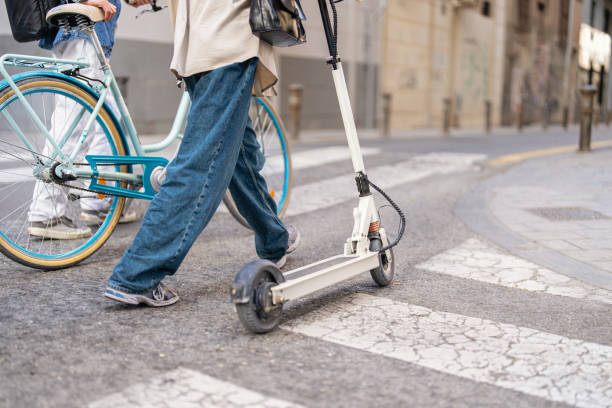Unrecognizable woman and man commuting through city with bicycle and electric push scooter stock photo