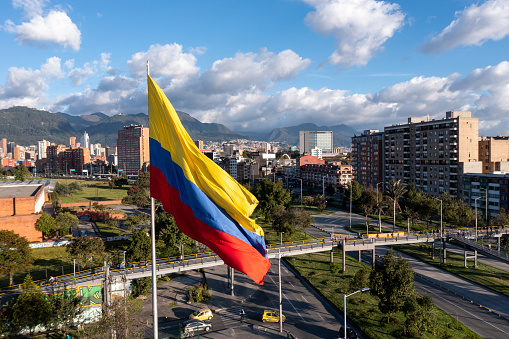 Photo of the Colombian flag on a pole with avenue and city buildings in the background. Bogota. Colombia. May 5, 2023.