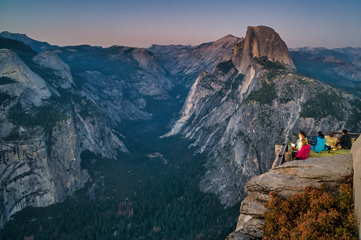 Visitors enjoy the view from Glacier Point lookout in Yosemite National Park, California, USA after sunset.