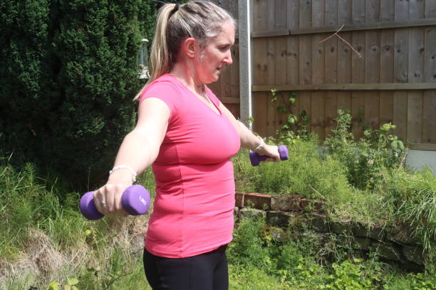 uma foto de uma mulher de meia-idade fazendo uma mistura de exercícios aeróbicos e anaeróbicos em seu jardim de casa - social media fotos - fotografias e filmes do acervo