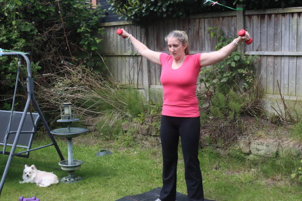 uma foto de uma mulher de meia-idade fazendo uma mistura de exercícios aeróbicos e anaeróbicos em seu jardim de casa - social media fotos - fotografias e filmes do acervo