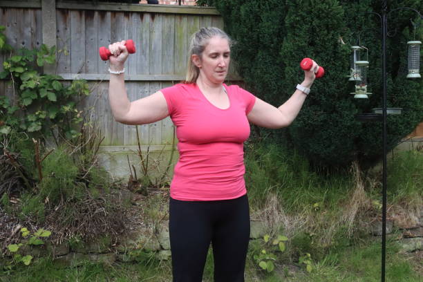 uma foto de uma mulher de meia-idade fazendo uma mistura de exercícios aeróbicos e anaeróbicos em seu jardim de casa - social media fotos - fotografias e filmes do acervo