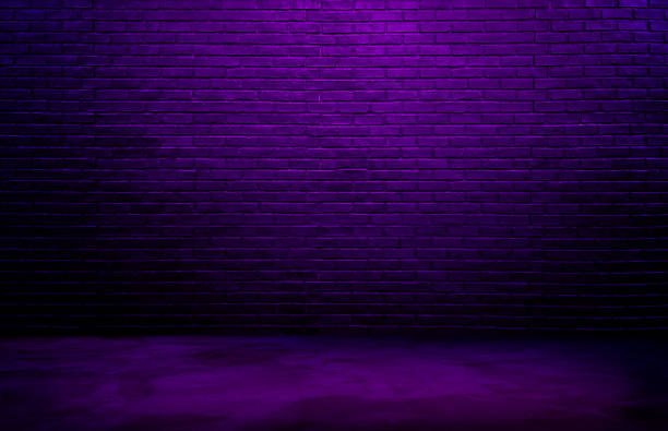 istock dark black brick wall background, rough concrete, plastered concrete floor, with neon purple glowing lights from above. lighting effect violet and blue on empty brick wall background for design. 1491542521